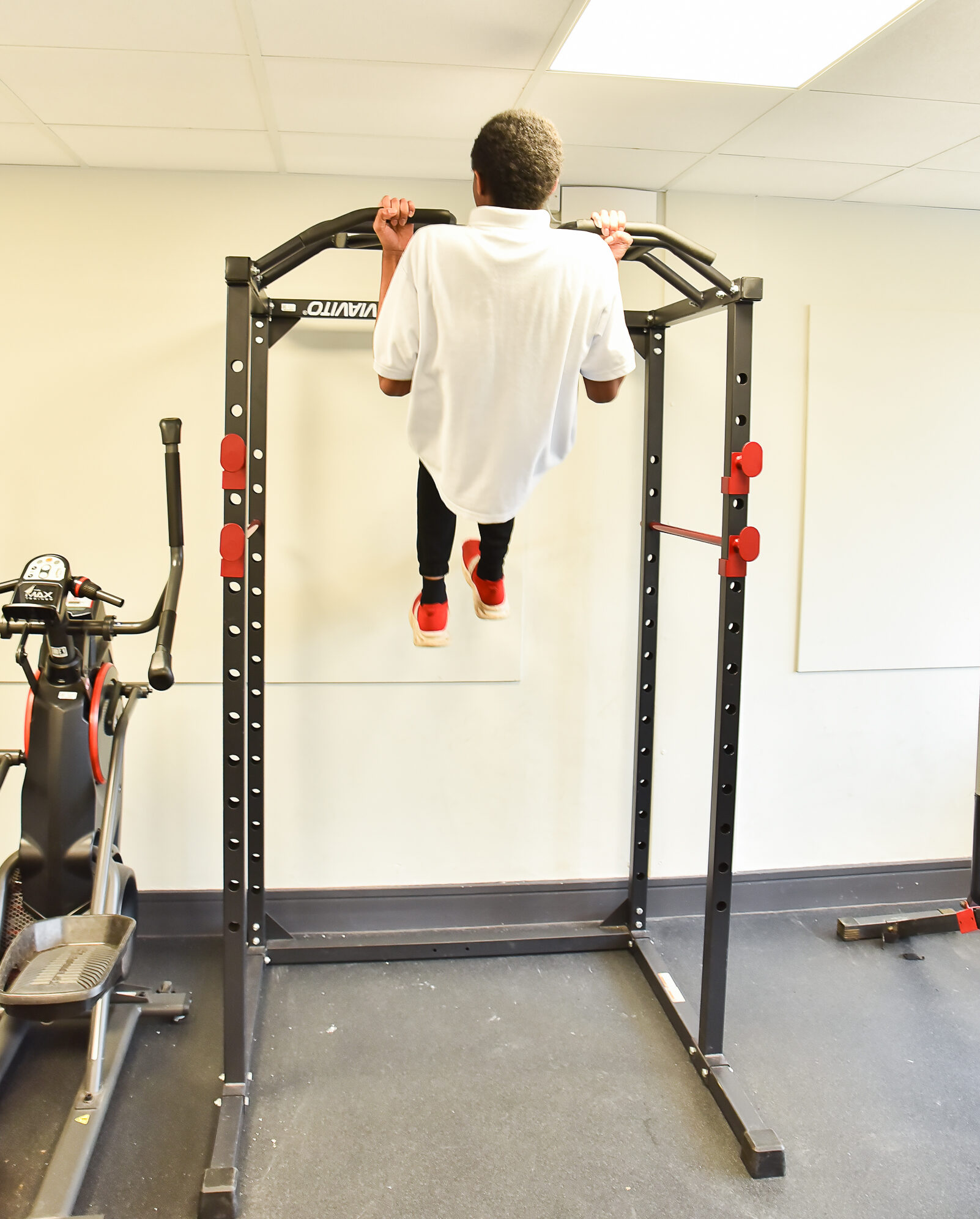 Pupil doing pull-ups on a gym frame in a school fitness room